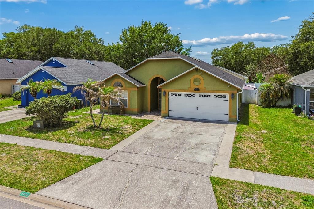 A green single-story house with a two-car garage and a concrete driveway — 1008 OLD BARN ROAD, ORLANDO, FL