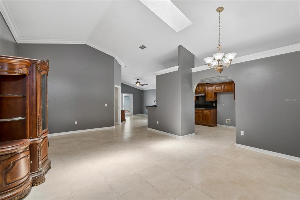 A spacious dining area with gray walls, tile flooring, and an arched entryway to the kitchen — 1008 OLD BARN ROAD, ORLANDO, FL
