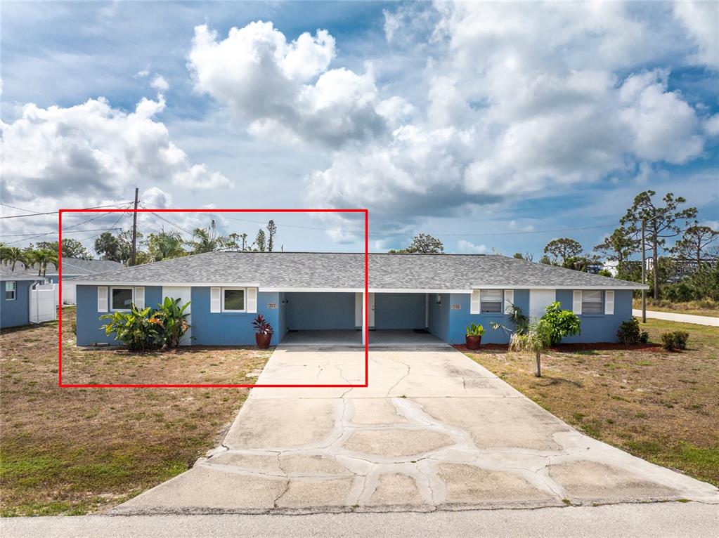 A blue duplex exterior features a shared driveway, covered carports, and a gray shingled roof — 1965 LOUISIANA AVENUE, ENGLEWOOD, FL