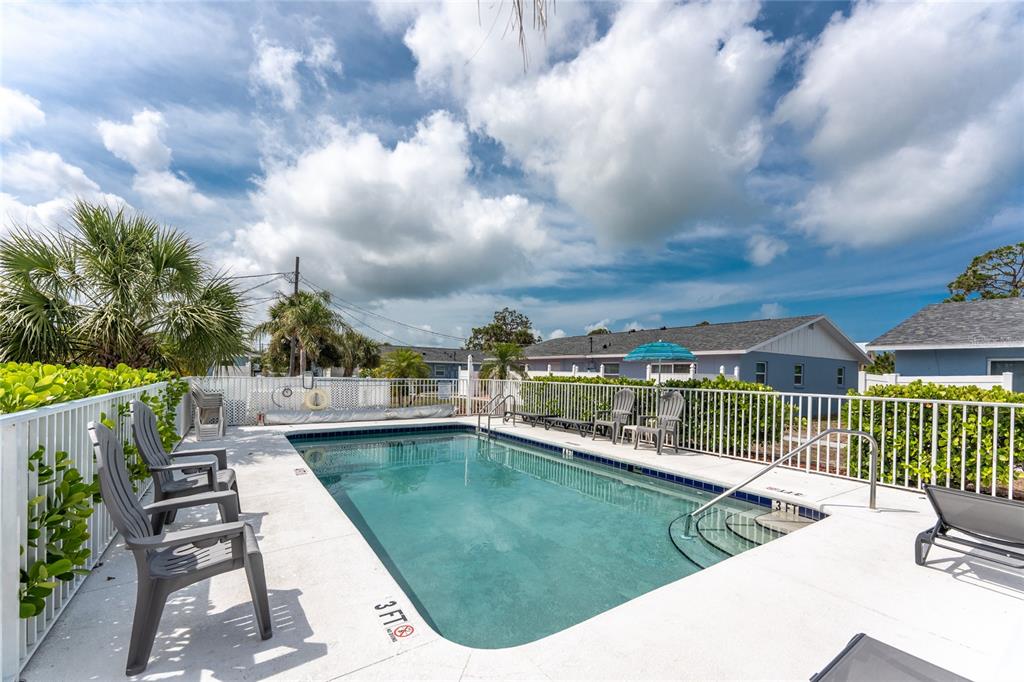 An outdoor swimming pool with a white fence, patio chairs, and a blue umbrella — 1965 LOUISIANA AVENUE, ENGLEWOOD, FL