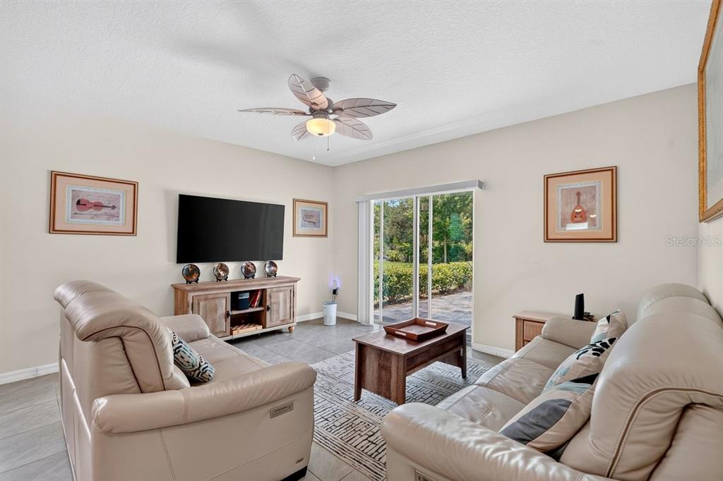 A living room features two leather sofas, a television on a wooden console, and sliding doors — 2757 PORTADOWN STREET, ORMOND BEACH, FL