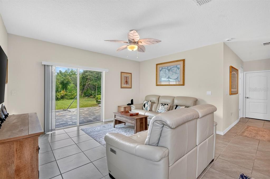 A living room features light tile floors, a ceiling fan, and sliding glass doors to a patio — 2757 PORTADOWN STREET, ORMOND BEACH, FL
