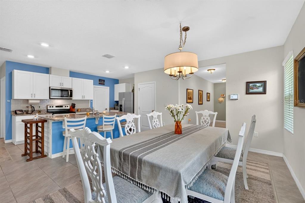 A dining area with a table and chairs sits adjacent to a kitchen with blue walls — 2757 PORTADOWN STREET, ORMOND BEACH, FL