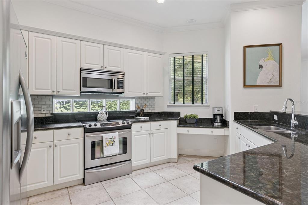 A kitchen features white cabinets, dark granite countertops, stainless steel appliances, and tile flooring — 134 LOWER LAKE COURT, DEBARY, FL