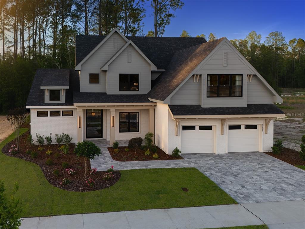 A two-story house with white brick, gray siding, and a two-car garage at dusk — 14828 SW 9TH LANE, NEWBERRY, FL