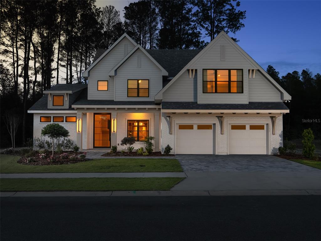 A two-story house with white siding, brick accents, and a two-car garage at dusk — 14828 SW 9TH LANE, NEWBERRY, FL