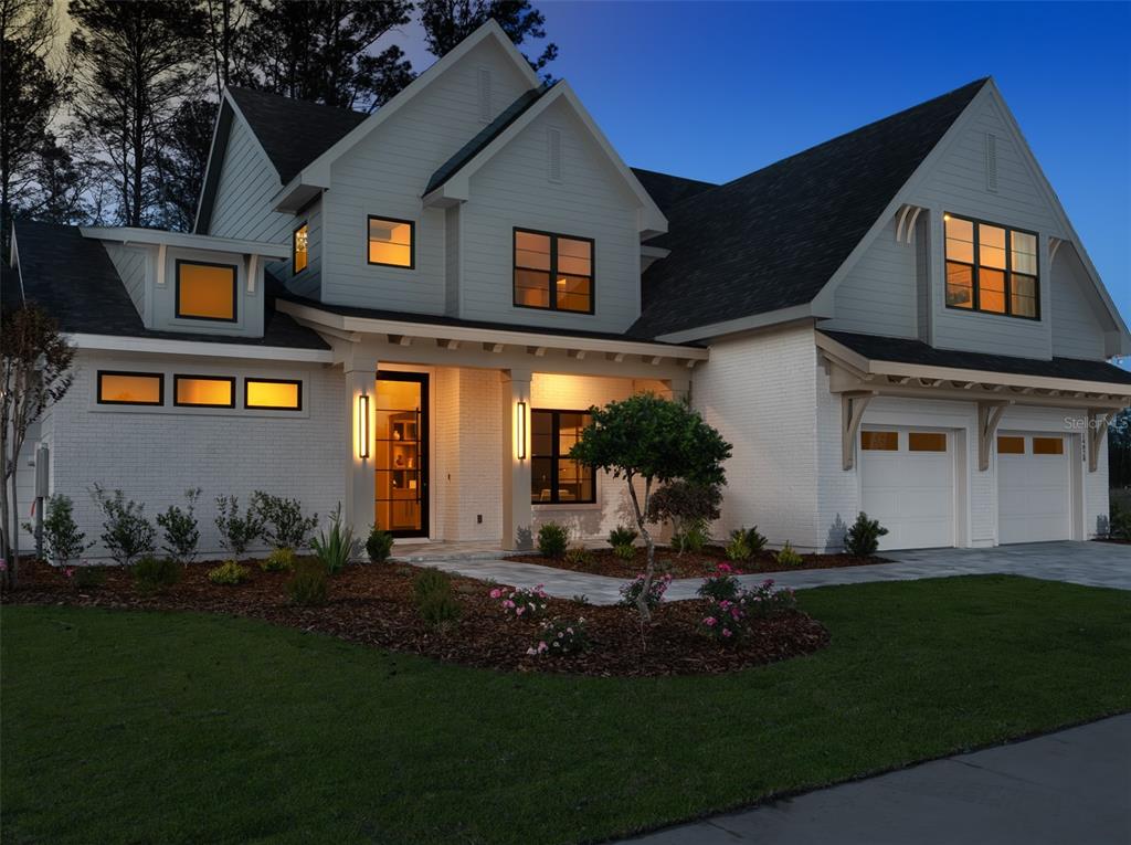 A two-story house with white brick, gray siding, and a two-car garage at dusk — 14828 SW 9TH LANE, NEWBERRY, FL