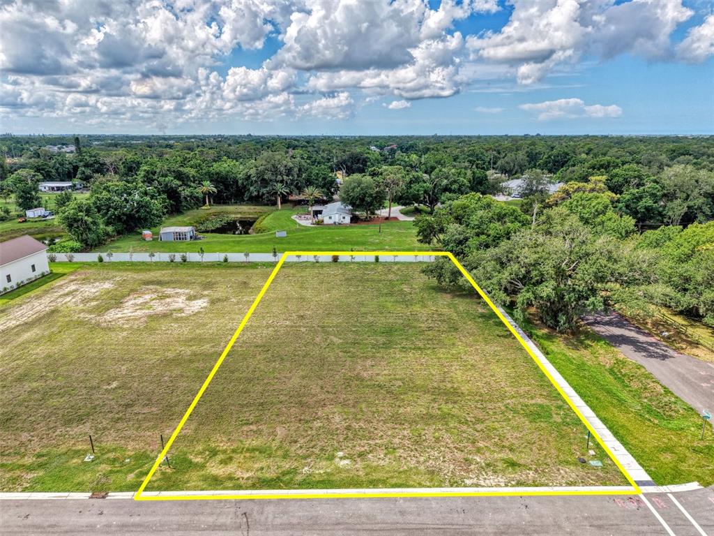 An aerial view shows a vacant, rectangular residential lot outlined in yellow along a road — 6601 PALADIN CT, SARASOTA, FL
