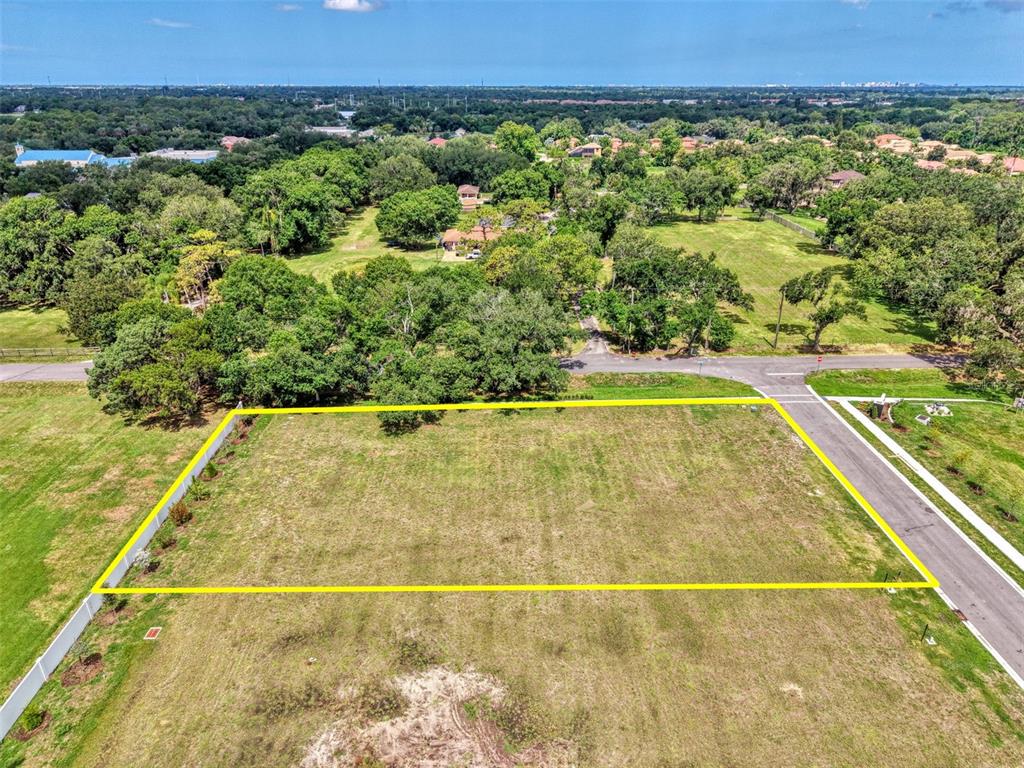 An aerial view shows a rectangular, vacant grassy lot outlined in yellow near a road — 6601 PALADIN CT, SARASOTA, FL