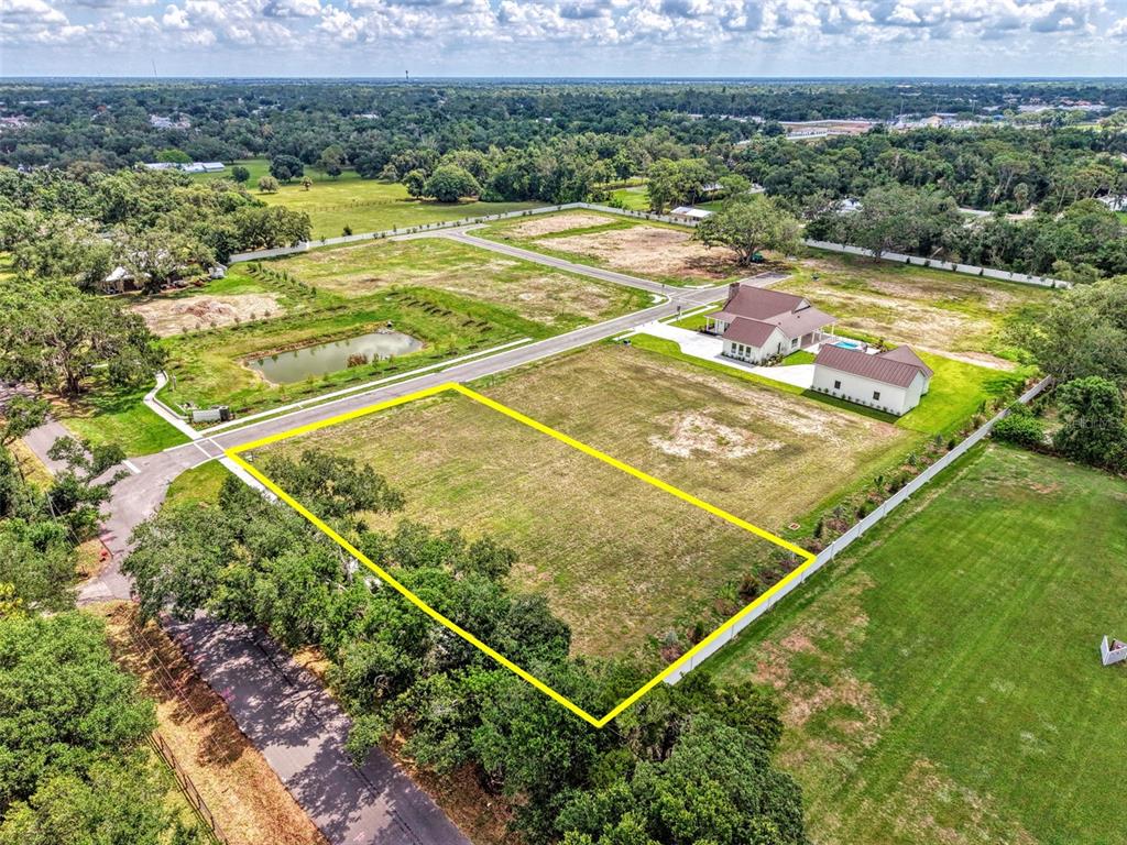 An aerial view shows a vacant, rectangular residential lot outlined in yellow near a house — 6601 PALADIN CT, SARASOTA, FL