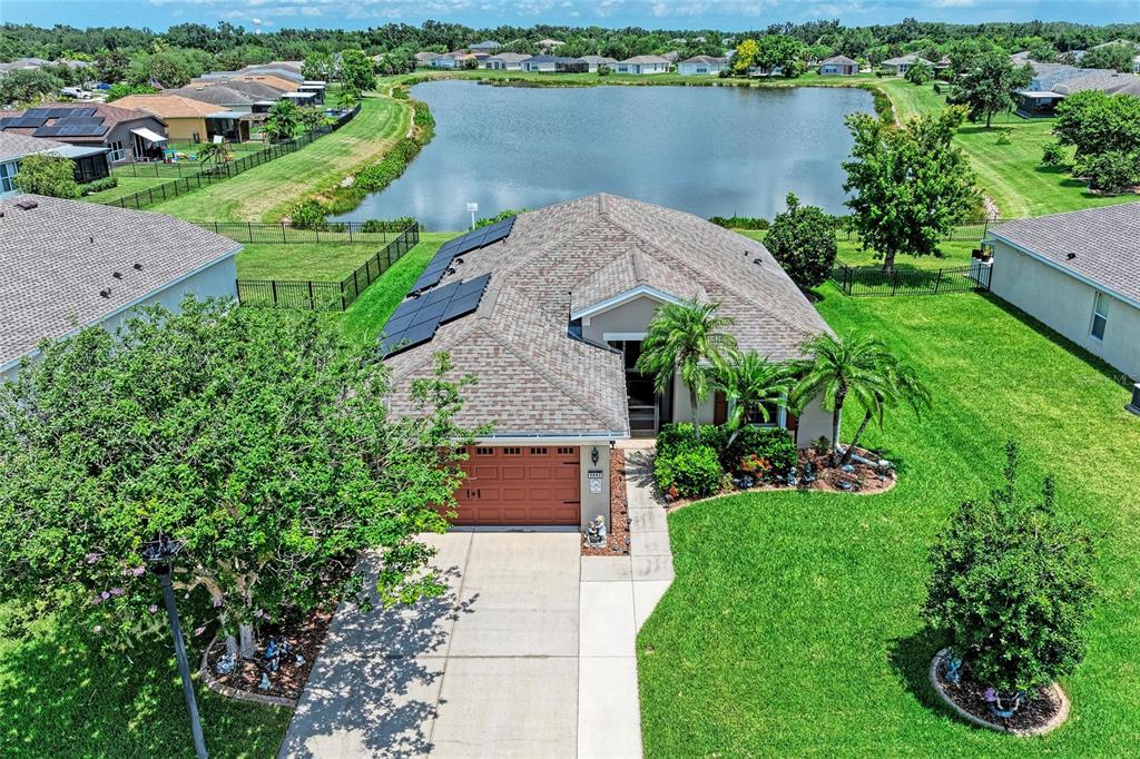 An aerial view of a suburban house with solar panels, a garage, and a lake — 9882 50TH STREET CIRCLE E, PARRISH, FL