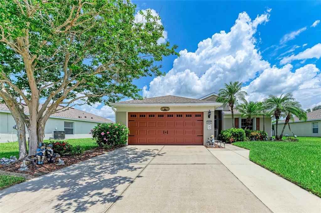 A single-story house with a brown garage door, concrete driveway, and a large front tree — 9882 50TH STREET CIRCLE E, PARRISH, FL