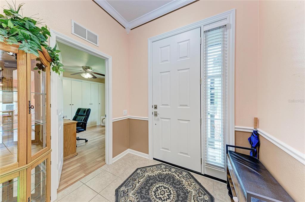 An entryway features a white front door, tile flooring, a rug, and a side room — 9882 50TH STREET CIRCLE E, PARRISH, FL