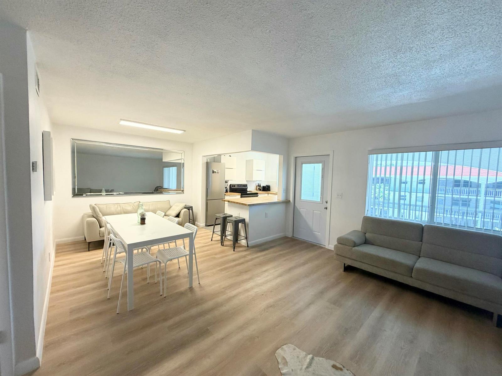 An open-concept living and dining area with light wood flooring, white walls, and a kitchen — 580 Egret Drive # 305, Hallandale Beach FL 33009, HALLANDALE BEACH, FL