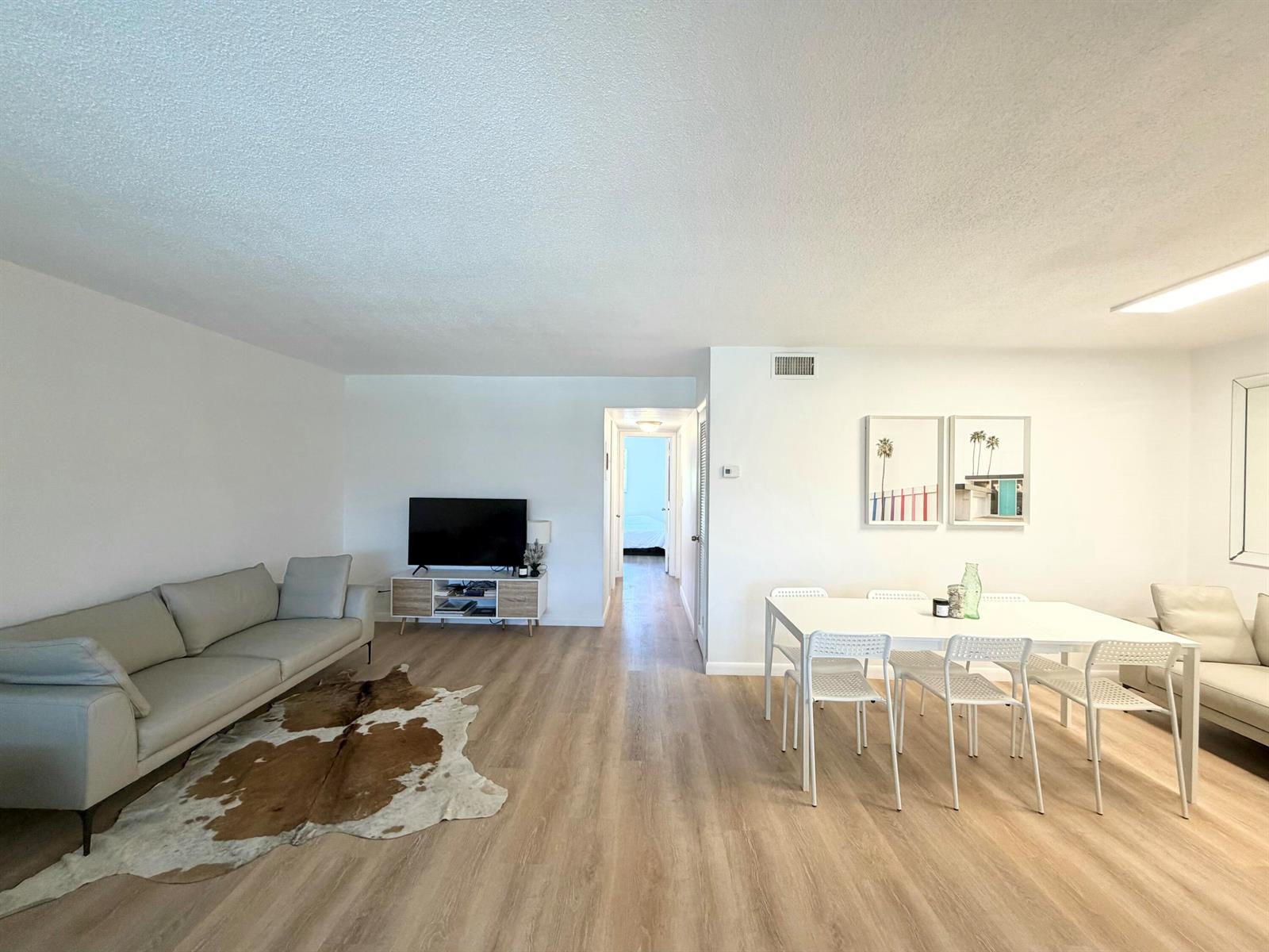 A living and dining area with light wood flooring, white walls, and modern furniture — 580 Egret Drive # 305, Hallandale Beach FL 33009, HALLANDALE BEACH, FL