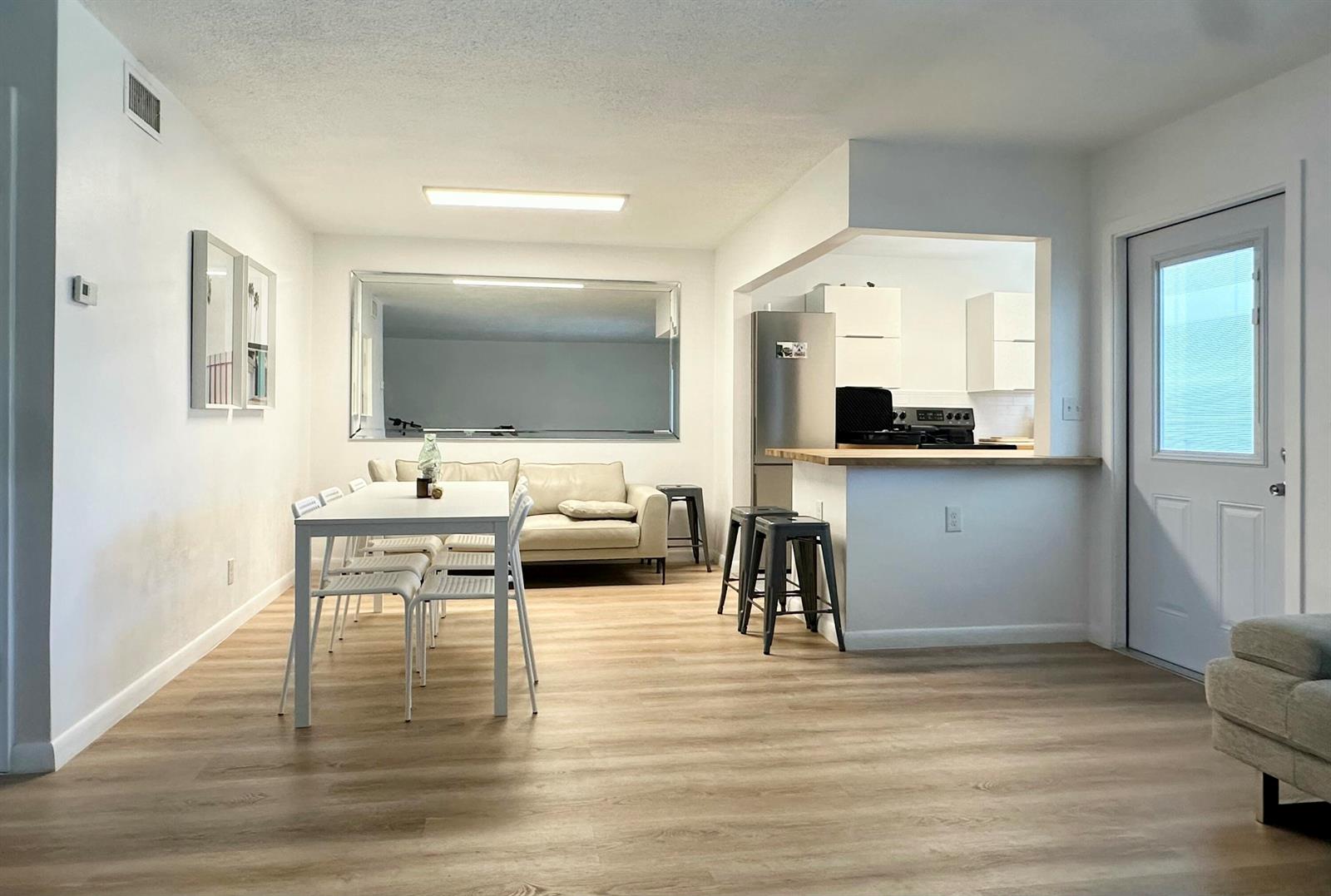 A dining area and kitchen with light wood-look flooring, white walls, and a breakfast bar — 580 Egret Drive # 305, Hallandale Beach FL 33009, HALLANDALE BEACH, FL