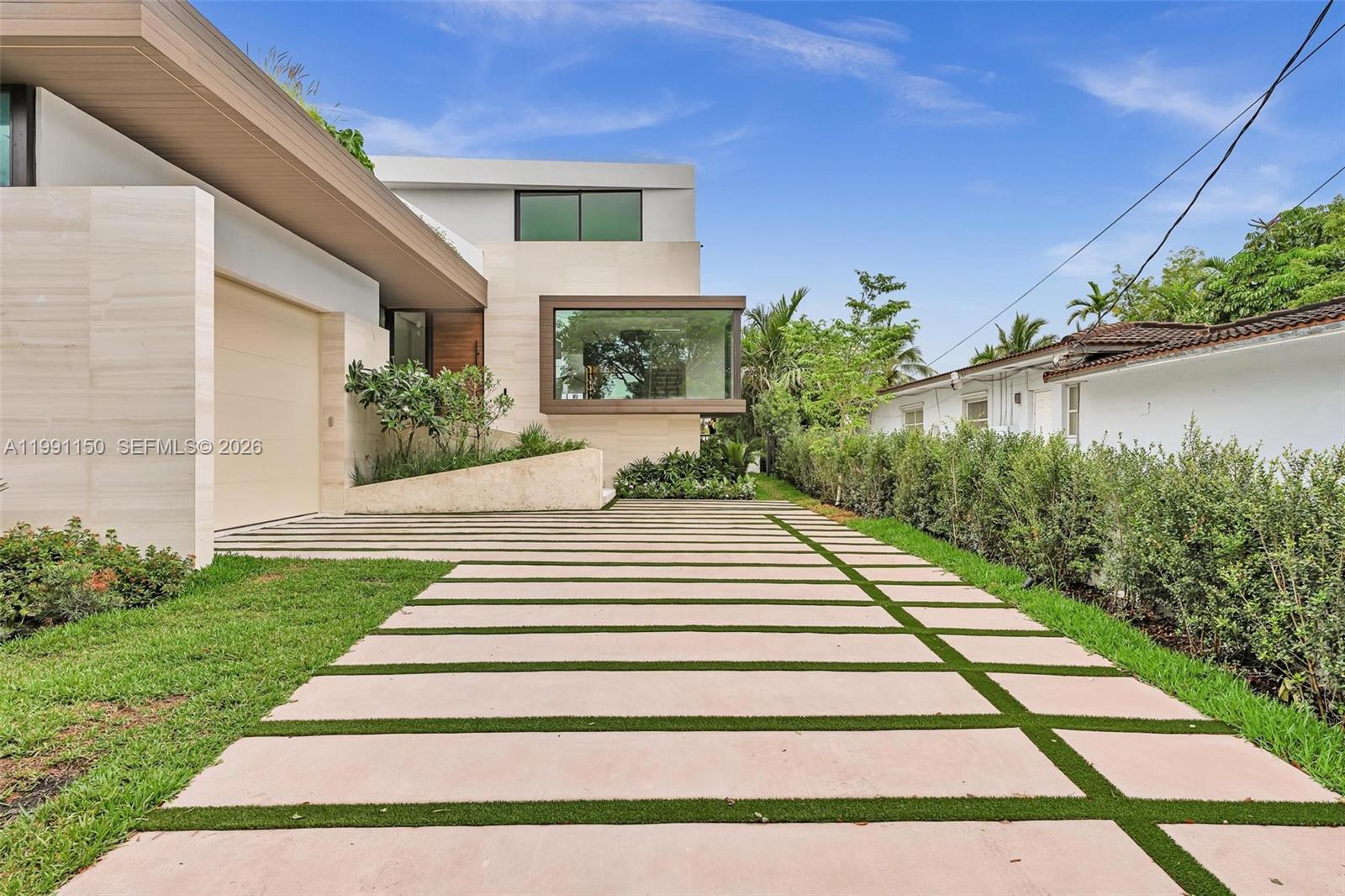 A modern house features a stone facade, a large glass window, and a paved driveway — 535 N Shore Dr, Miami Beach FL 33141, MIAMI BEACH, FL