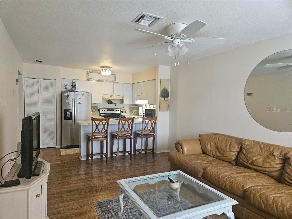 A living room with a leather sofa and a kitchen with a breakfast bar — 810 KINGS COURT UNIT B, PUNTA GORDA, FL