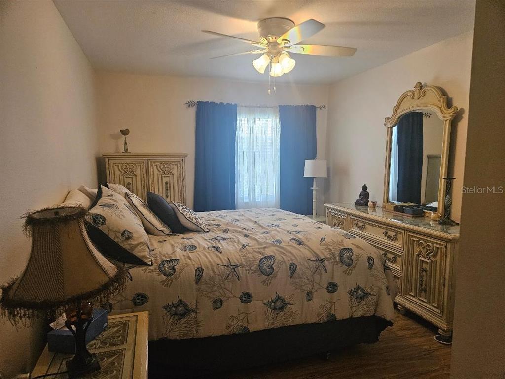 A bedroom features a bed with seashell bedding, a dresser with a mirror, and curtains — 810 KINGS COURT UNIT B, PUNTA GORDA, FL