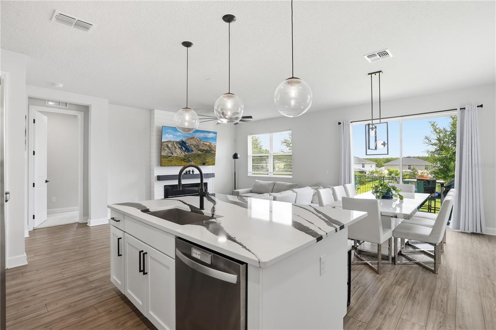 A kitchen island with a quartz countertop sits in an open-concept living and dining area — 2784 PARK RIDGE STREET, APOPKA, FL