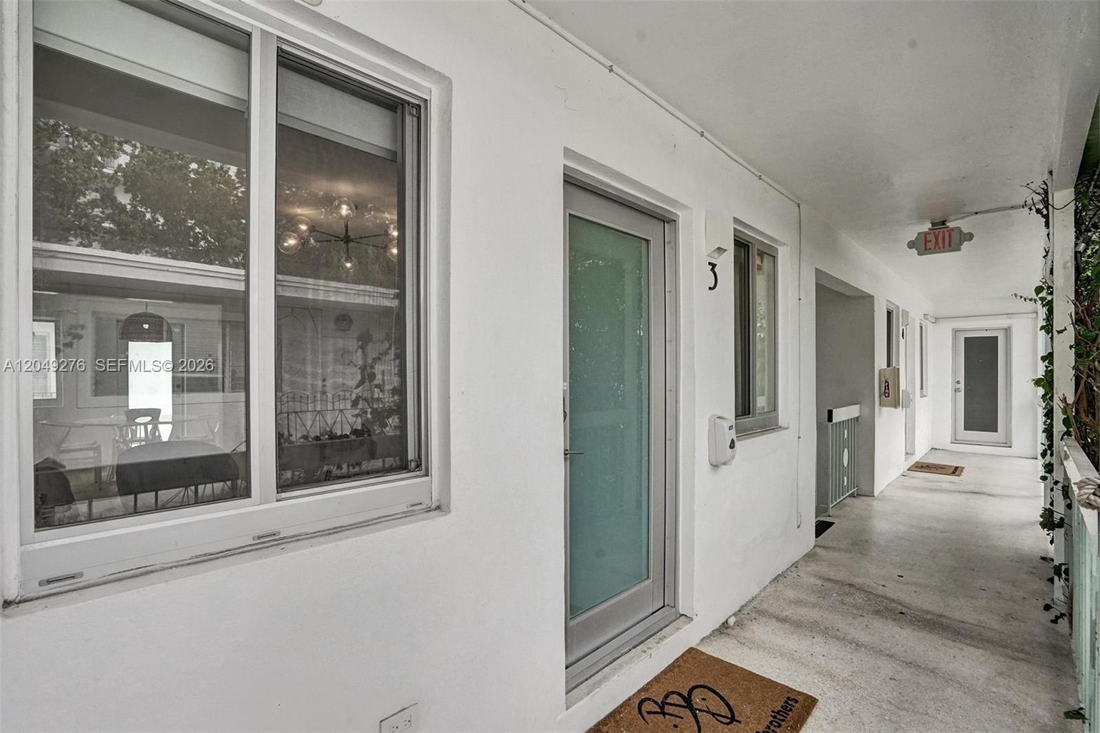 An exterior view of a white building hallway featuring a numbered door and windows — 1440 16th St # 3, Miami Beach FL 33139, MIAMI BEACH, FL