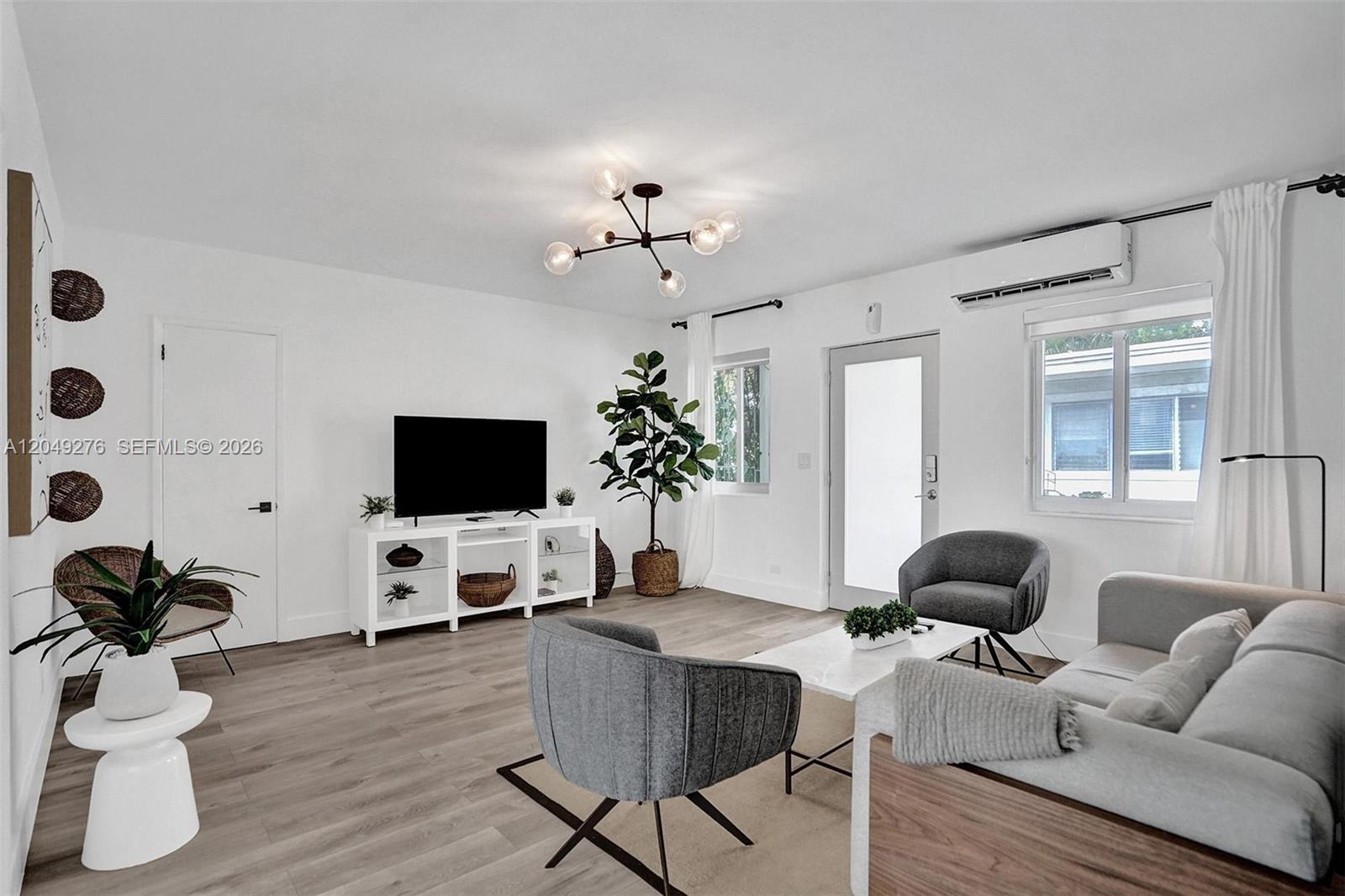 A bright living room features a television, modern furniture, a ceiling light, and wood flooring — 1440 16th St # 3, Miami Beach FL 33139, MIAMI BEACH, FL