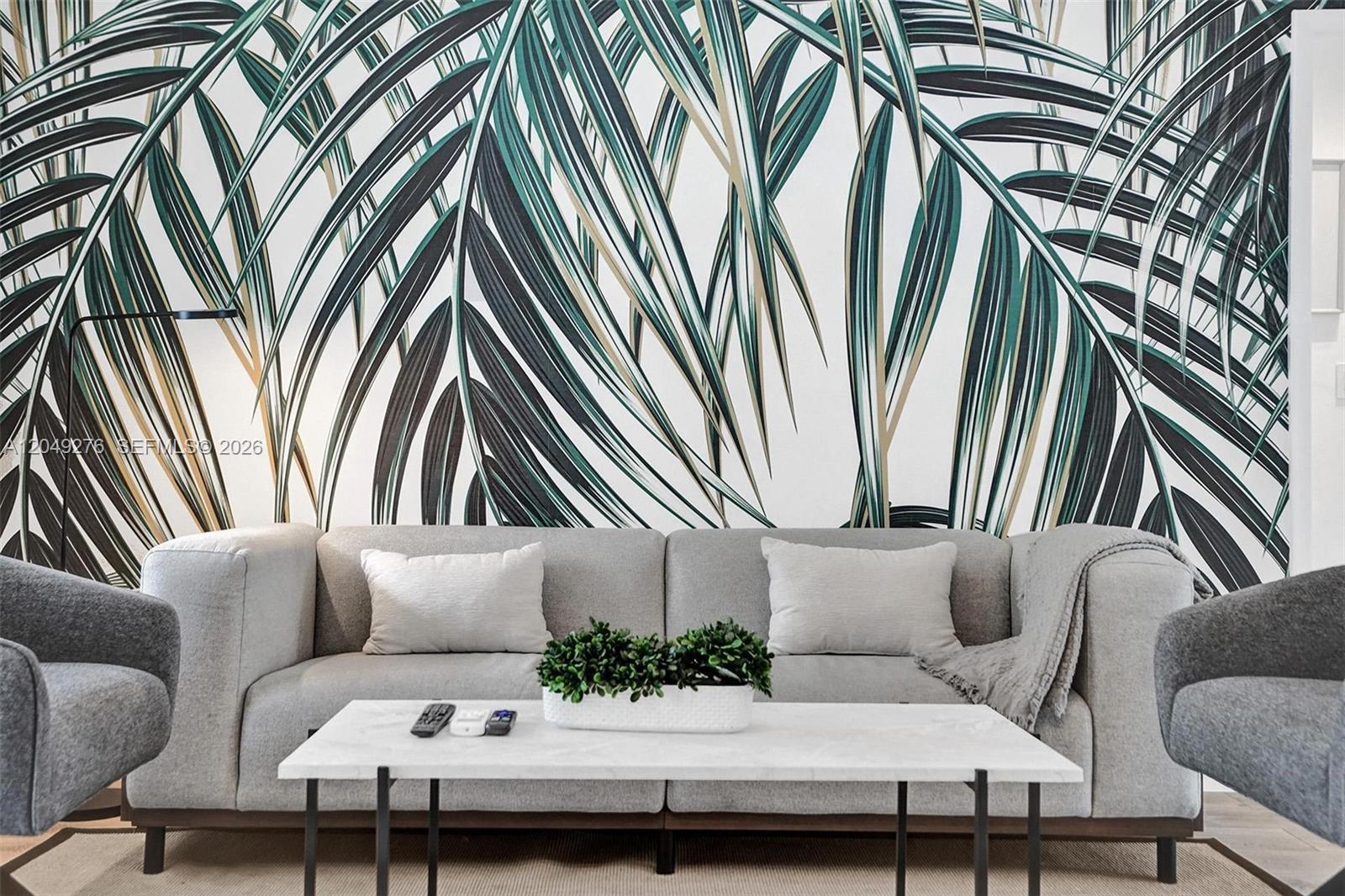 A living room features a grey sofa, a marble coffee table, and palm leaf wallpaper — 1440 16th St # 3, Miami Beach FL 33139, MIAMI BEACH, FL