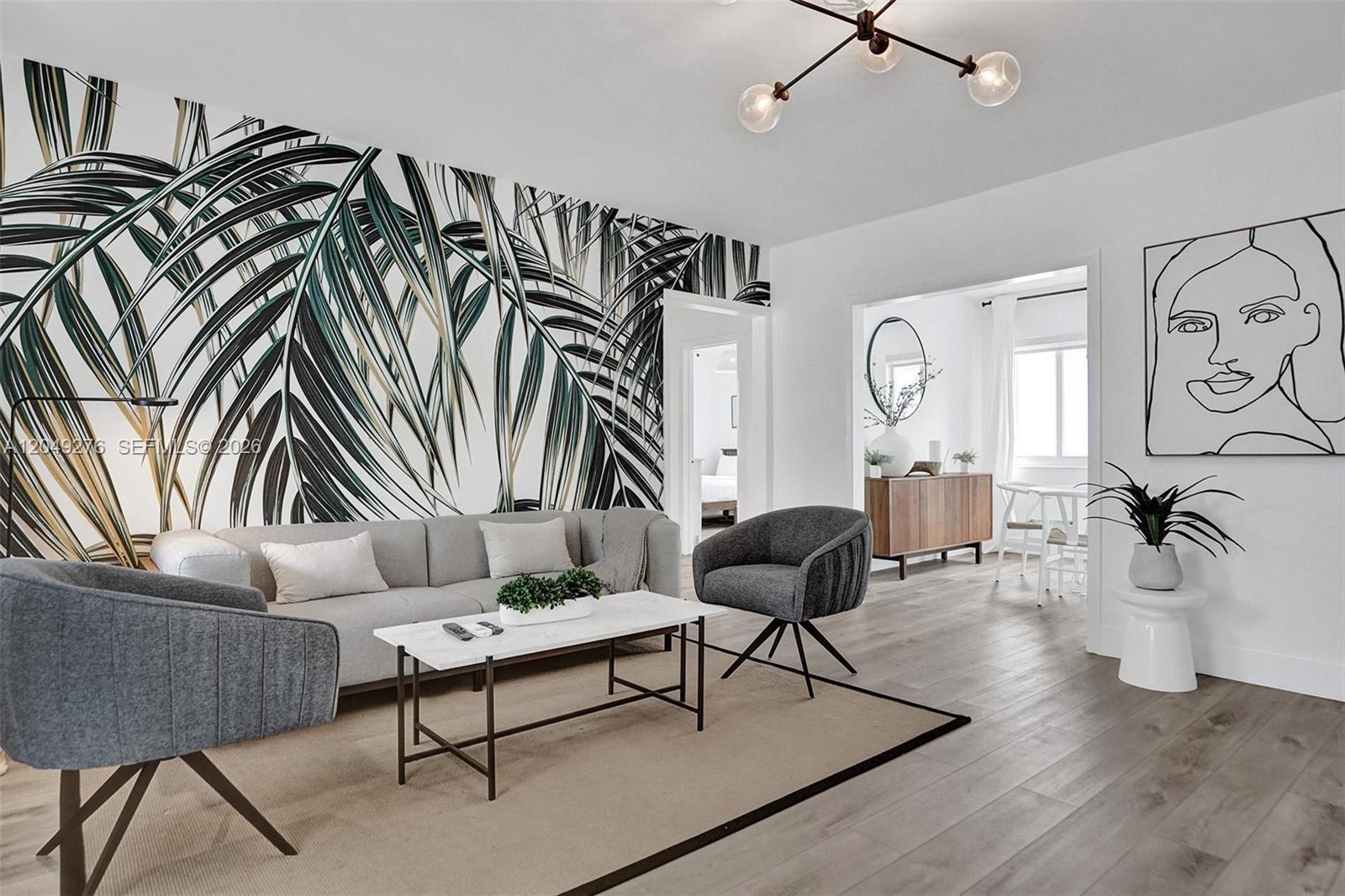 A living room features a palm leaf accent wall, grey furniture, and light wood flooring — 1440 16th St # 3, Miami Beach FL 33139, MIAMI BEACH, FL