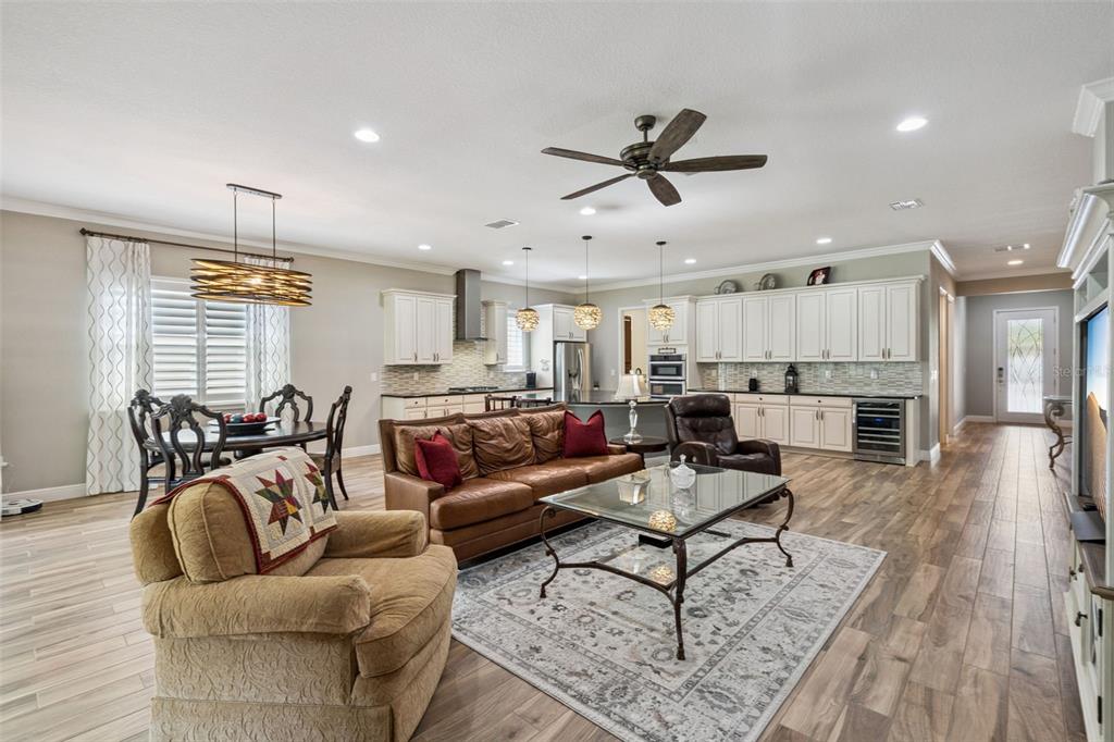 An open-concept living room and kitchen feature wood-look tile floors and white cabinetry — 4912 CATALPA DRIVE, ST CLOUD, FL