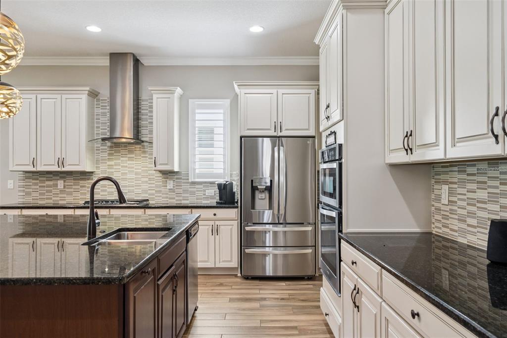 A kitchen features white cabinets, dark granite countertops, stainless steel appliances, and a center island — 4912 CATALPA DRIVE, ST CLOUD, FL