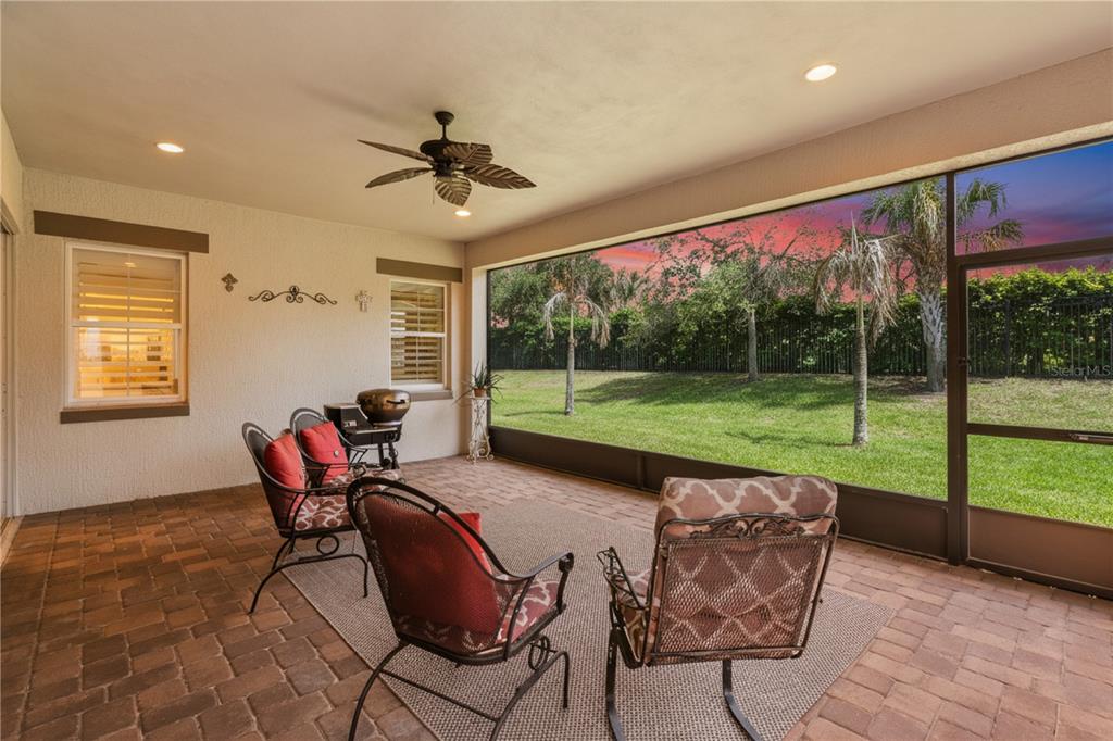 A covered patio with brick pavers, outdoor furniture, and a screened view of a grassy yard — 4912 CATALPA DRIVE, ST CLOUD, FL