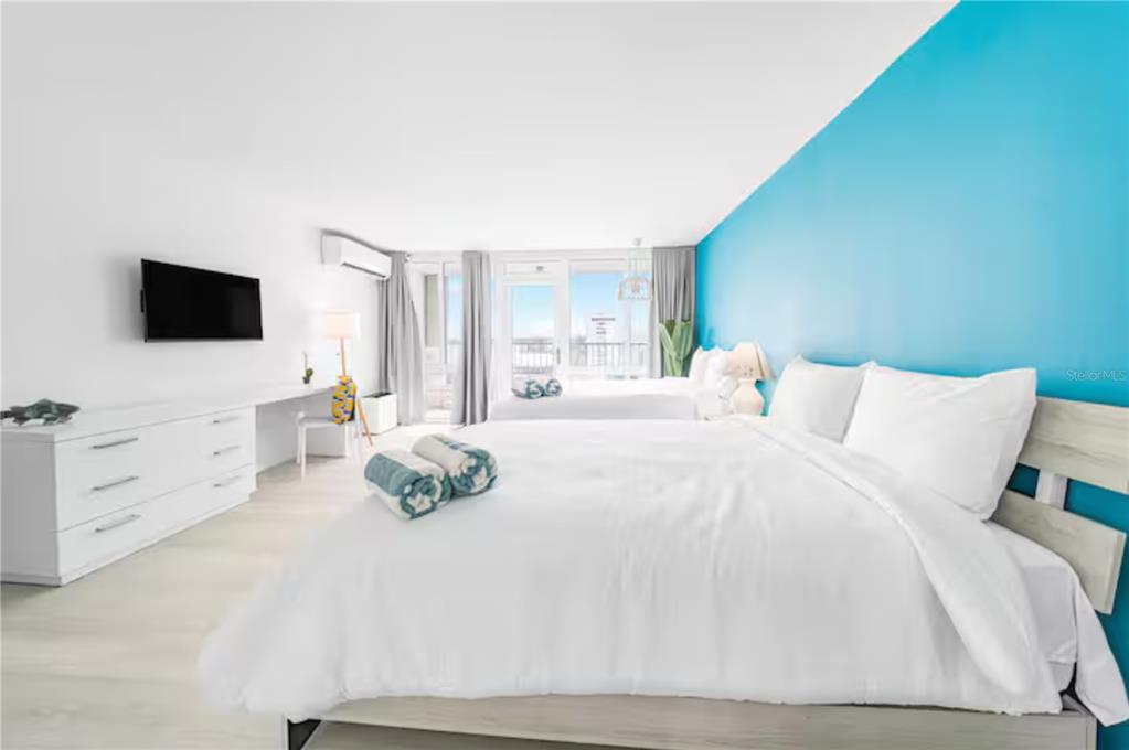 A bedroom features two beds, white furniture, a blue accent wall, and a balcony view — 6165 AV. ISLA VERDE UNIT 659, CAROLINA, PR