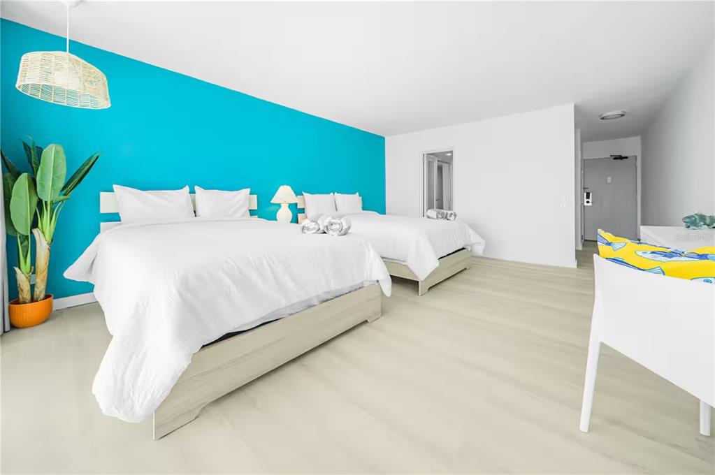 A bedroom features two beds, a bright turquoise accent wall, and light wood-look flooring — 6165 AV. ISLA VERDE UNIT 659, CAROLINA, PR