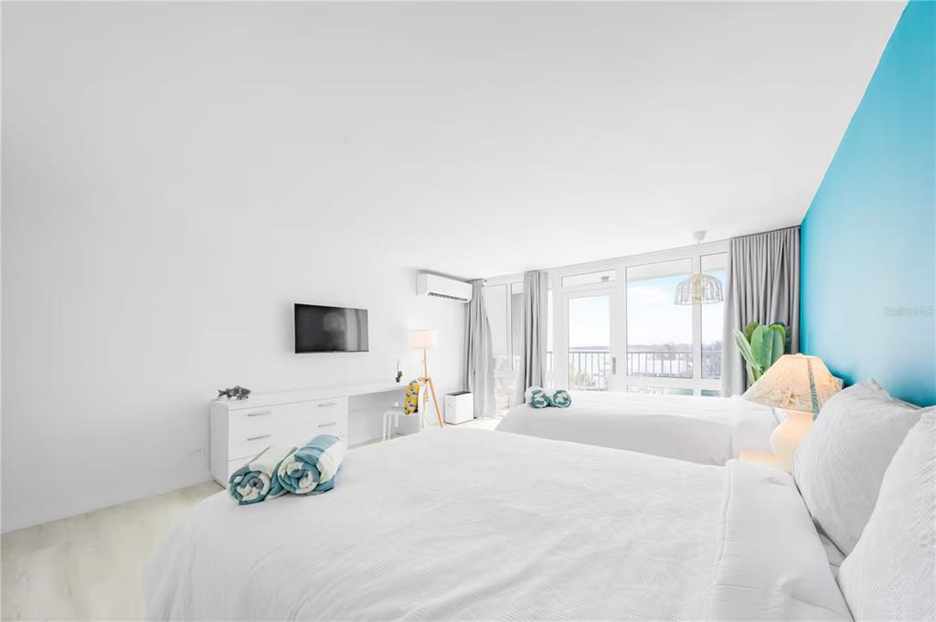 A bedroom with two white beds, a long desk, and a balcony with water views — 6165 AV. ISLA VERDE UNIT 659, CAROLINA, PR