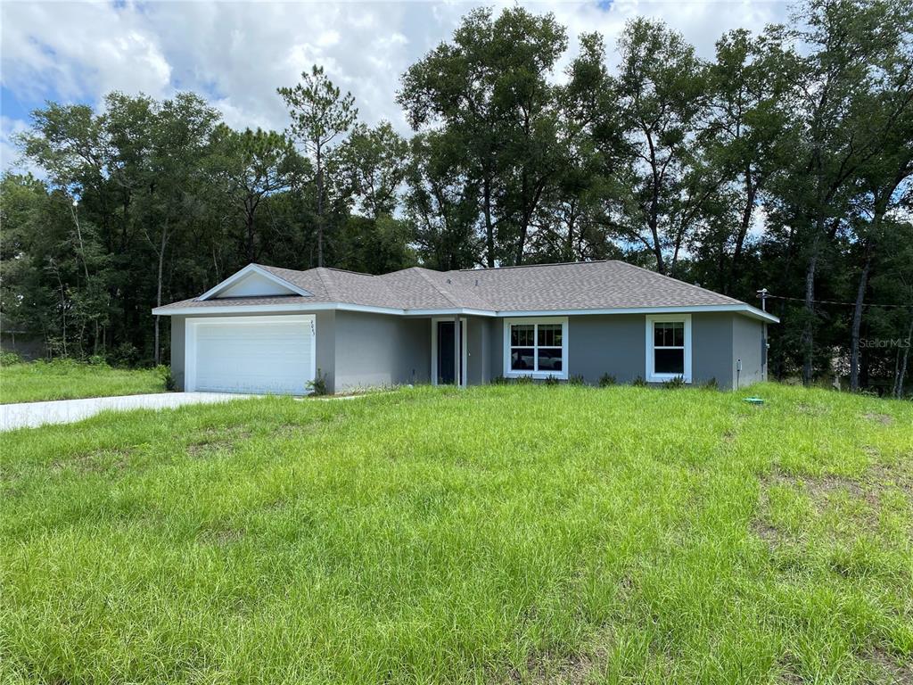 A single-story gray house with a two-car garage sits on a grassy lot — 9065 N AKOLA WAY, CITRUS SPRINGS, FL