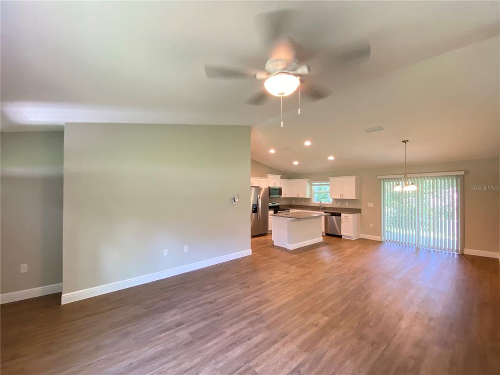 An open-concept living area features wood-look flooring, a ceiling fan, and a kitchen with white cabinets — 9065 N AKOLA WAY, CITRUS SPRINGS, FL