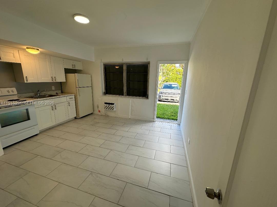 A kitchen with white cabinets, light tile flooring, and an exterior door leading outside — 1293 NE 109th St # 3, Miami FL 33161, MIAMI, FL
