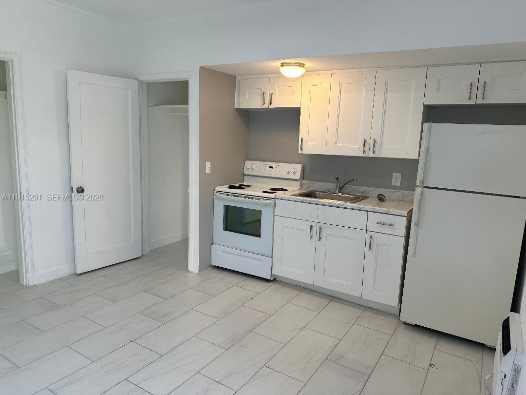 A kitchen features white cabinets, white appliances, and light-colored tile flooring — 1293 NE 109th St # 3, Miami FL 33161, MIAMI, FL