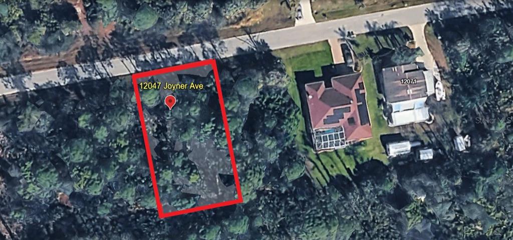 An aerial view shows a rectangular, wooded vacant lot outlined in red next to houses — 12047 JOYNER AVENUE, PORT CHARLOTTE, FL