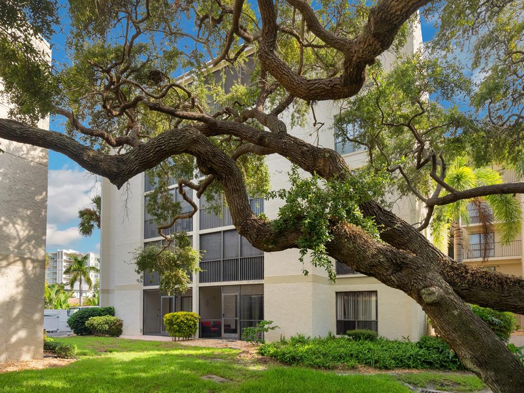 An aerial view shows a multi-story apartment building with a swimming pool in the courtyard — 6157 MIDNIGHT PASS ROAD UNIT E12, SARASOTA, FL