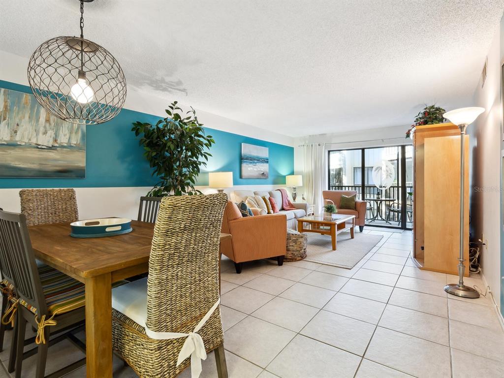 A living room features a bright blue accent wall, tile flooring, and a sliding glass door — 6157 MIDNIGHT PASS ROAD UNIT E12, SARASOTA, FL