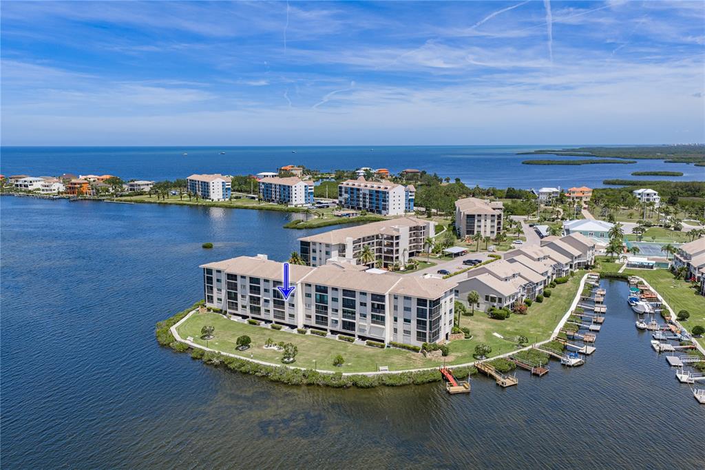 An aerial view shows a multi-story waterfront condominium complex with a boat dock nearby — 8150 BRENT STREET UNIT 725, PORT RICHEY, FL