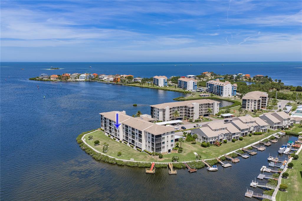 An aerial view shows a multi-story waterfront condominium complex with a blue arrow pointing down — 8150 BRENT STREET UNIT 725, PORT RICHEY, FL