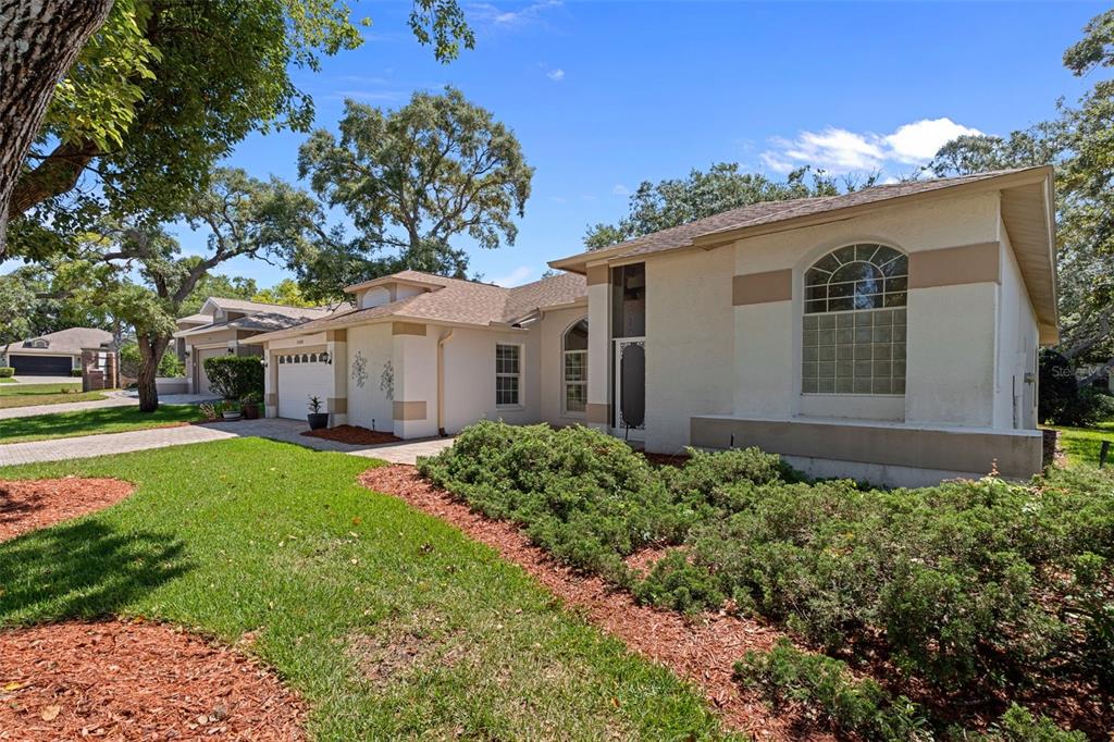 A single-story house with a beige stucco exterior, a two-car garage, and a large arched window — 2086 SPARKLING WATERS WAY, SPRING HILL, FL