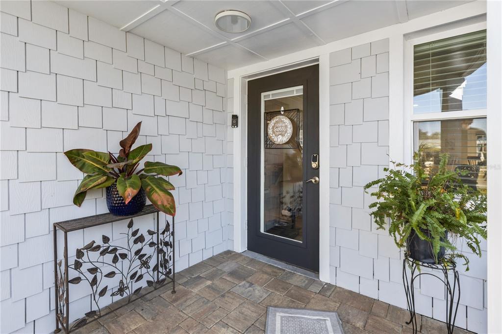 A front porch features gray shingle siding, a dark door, and two potted plants — 3122 N REGATTA CIRCLE, SARASOTA, FL