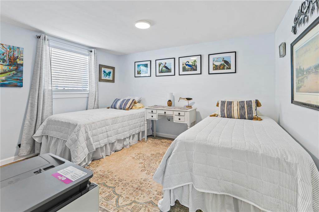 A bedroom features two twin beds, a small desk, and framed artwork on the walls — 3122 N REGATTA CIRCLE, SARASOTA, FL