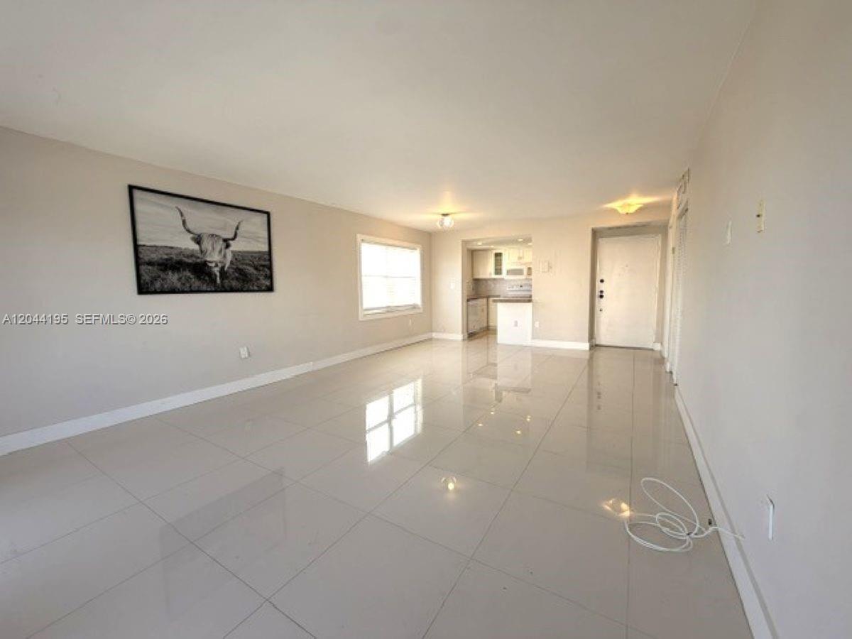 A bright, open-concept living area features large light-colored floor tiles and a neutral wall color — 4141 Nautilus Dr # 4J, Miami Beach FL 33140, MIAMI BEACH, FL