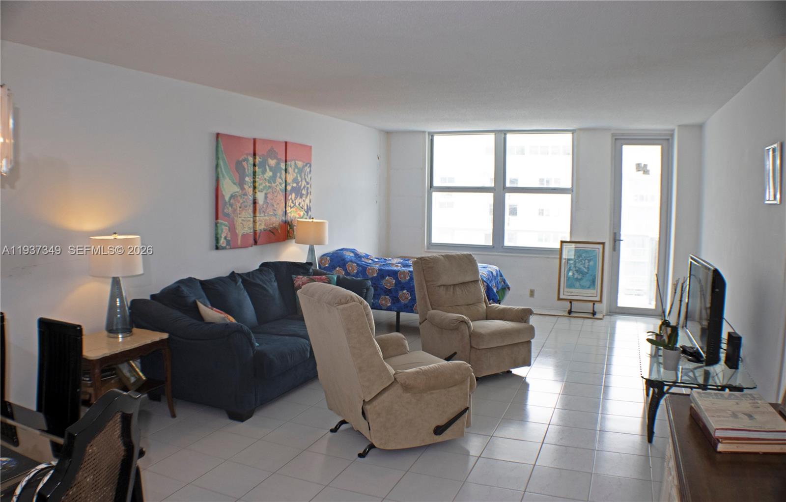 A living room features a blue sofa, two beige recliners, tile flooring, and a bed — 9511 Collins Ave # 1108, Surfside FL 33154, SURFSIDE, FL