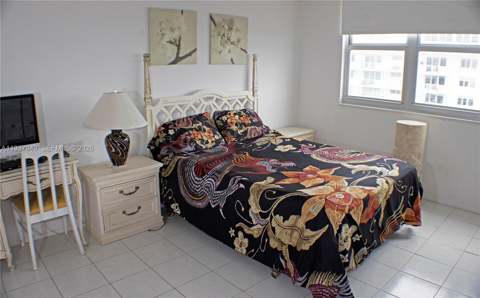 A bedroom features a bed with a patterned quilt, a desk, and tiled flooring — 9511 Collins Ave # 1108, Surfside FL 33154, SURFSIDE, FL