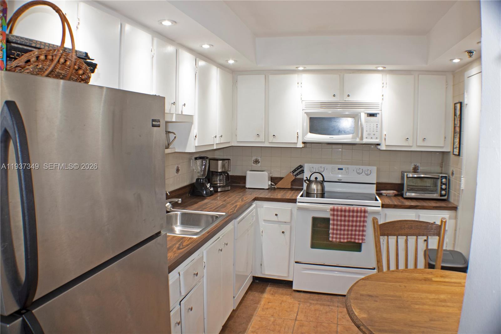 A kitchen features white cabinets, stainless steel appliances, and dark wood-look countertops — 9511 Collins Ave # 1108, Surfside FL 33154, SURFSIDE, FL